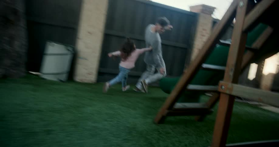 Father and daughter running around the yard