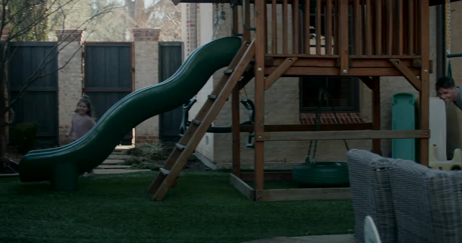 A father and daughter run around the playground together