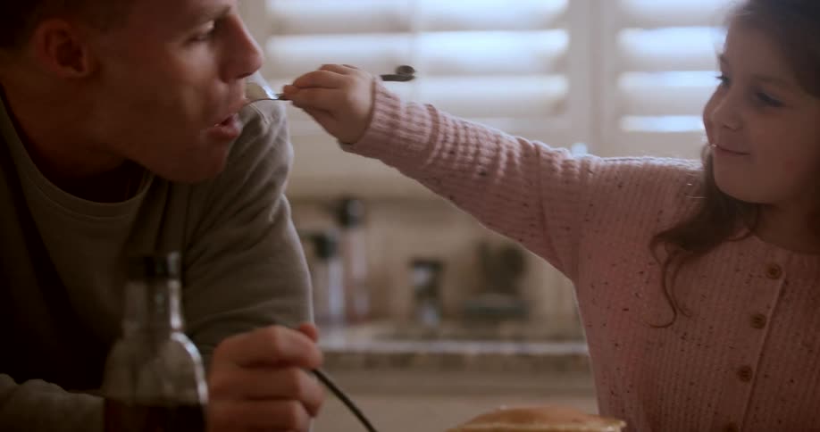 A daughter feeds her dad pancakes
