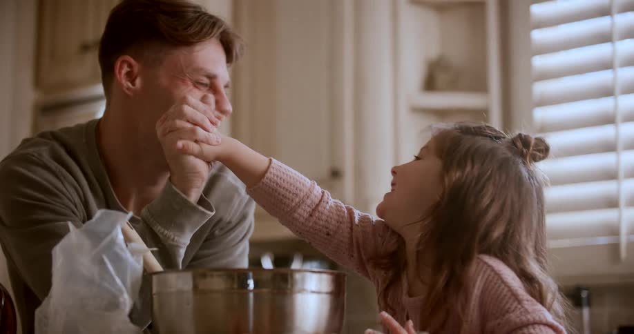 A father and daughter high five while they are cooking