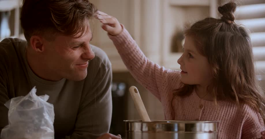 A girl plays around putting flour on her fathers face