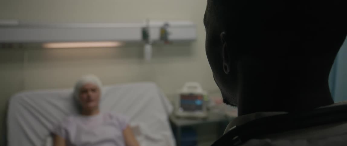 A doctor is standing at the end of a bed talking to a patient in the hospital