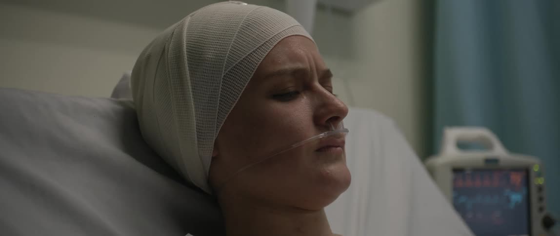 A woman in the hospital bed has bandages on her head