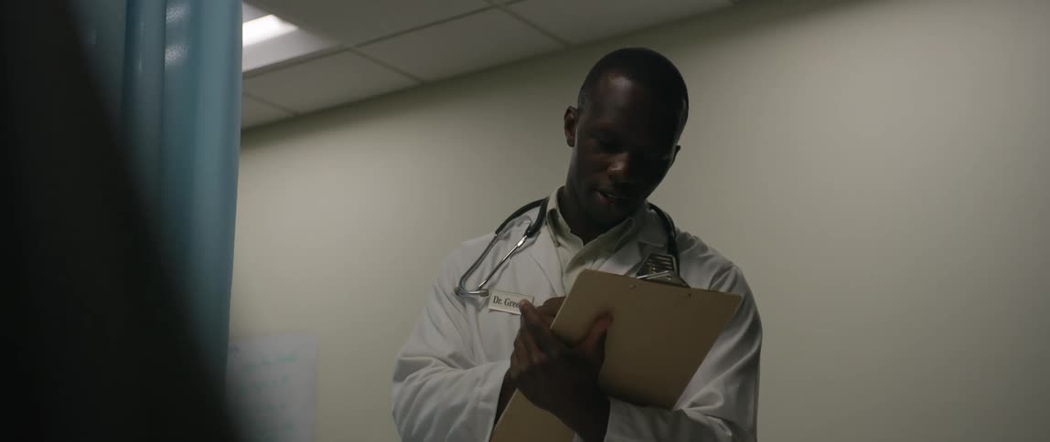 A doctor takes notes and smiles at the patient