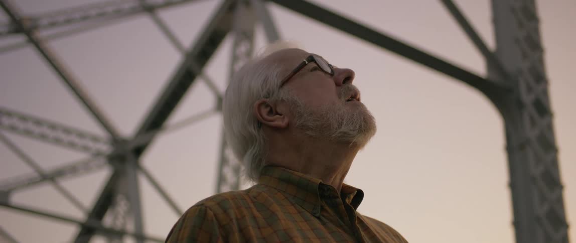 A man looks around a steel bridge