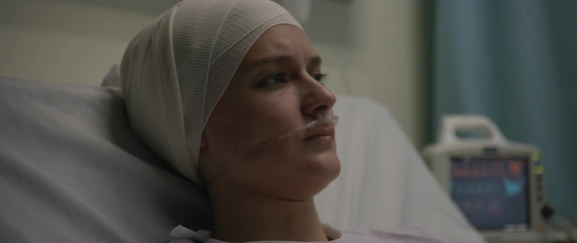 Woman with bandages on her head lying in a hospital bed slowly wakes
