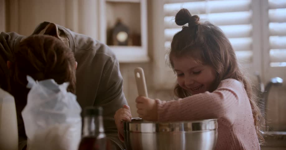 Smiling father and daughter having fun and making food in the kitchen
