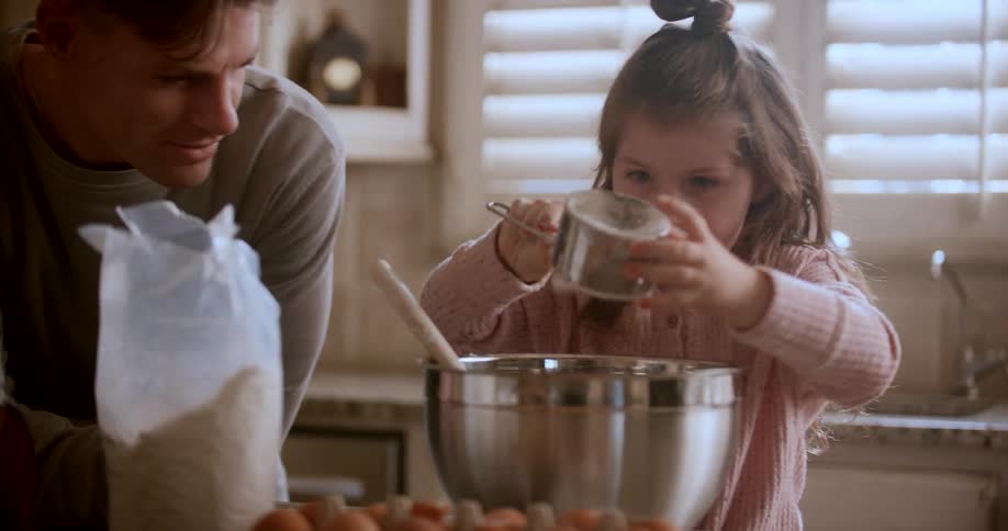 A father and daughter are mixing up something to bake in the kitchen