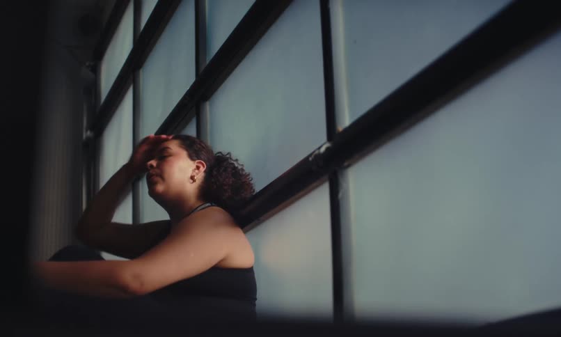 A woman is sitting against the window while resting in the gym
