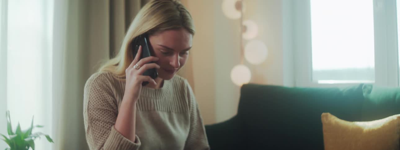 A woman is talking on her cell phone while browsing a laptop