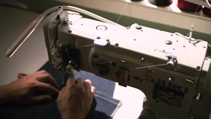 A tailor is using a sewing machine on the fabric