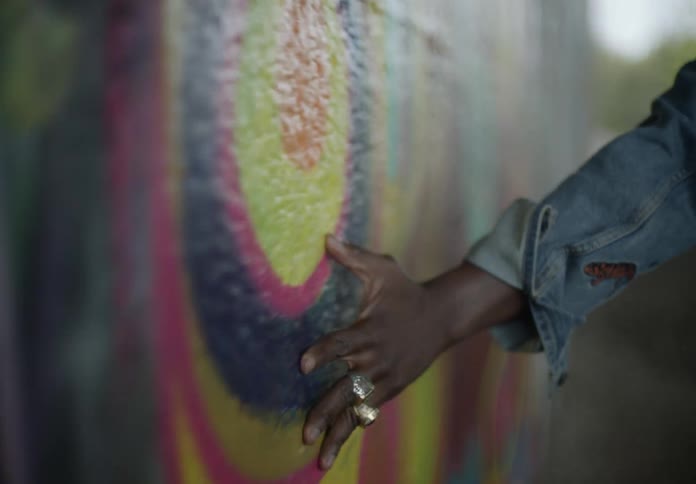 Close up of a persons hand passing through a wall with artistic painting