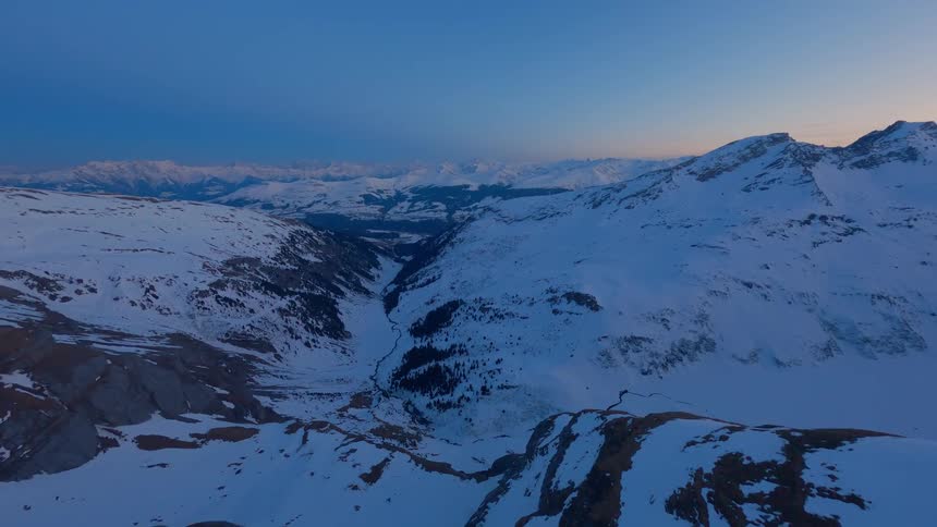 A large snowy mountain range at golden hour