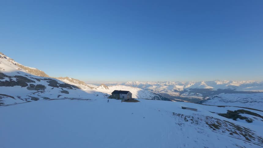 Aerial view of a mountain valley and a secluded wooden lodge in Switzerland