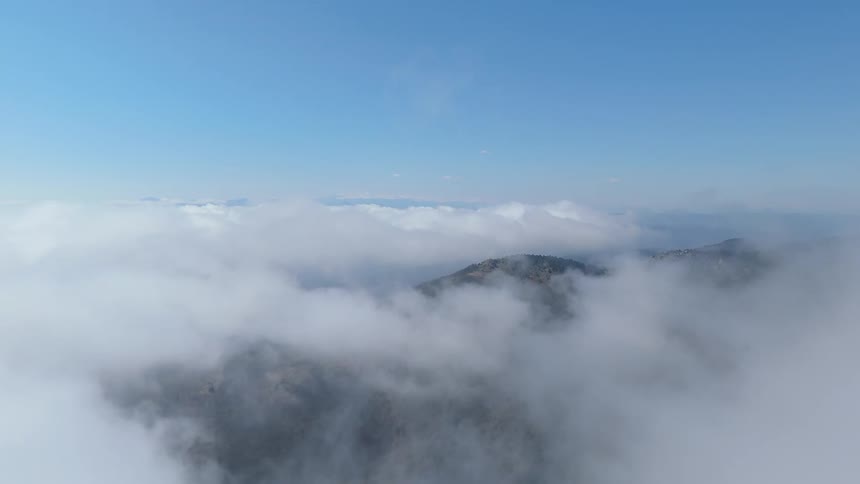A blue sky with many clouds and mountains on the ground