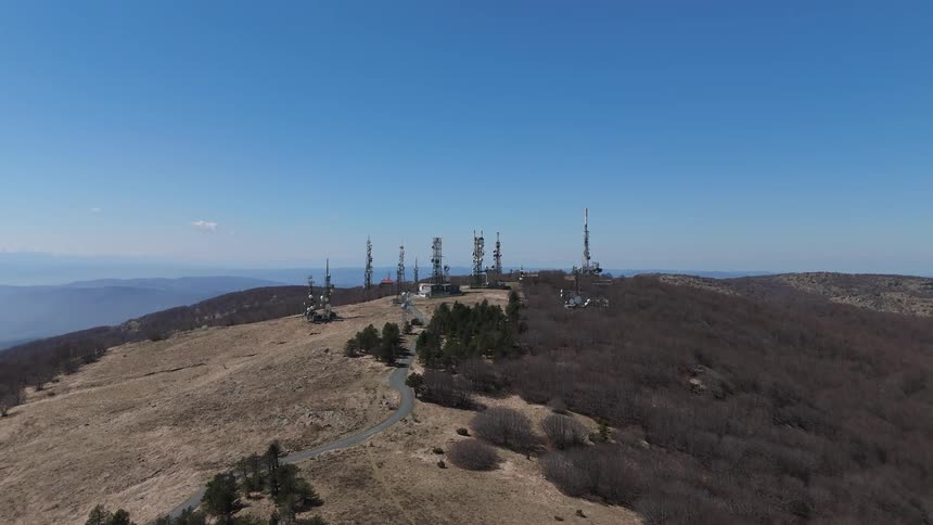 Aerial view of a mountain peak with several communication antennas
