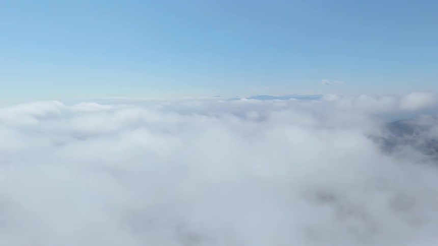 Clouds and a blue sky with distant mountains on the horizon
