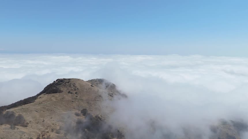 Flight over a mountain range above the clouds