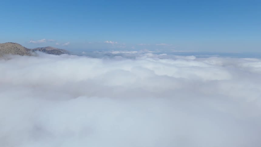 Aerial view of a mountain range rising above the clouds
