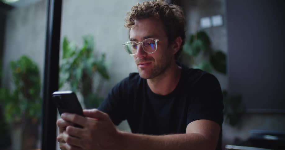 Man wearing glasses sitting interacting with a smartphone