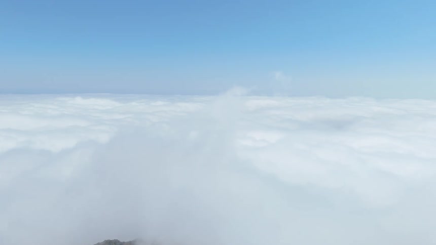 The mountain peak touches the sky full of clouds
