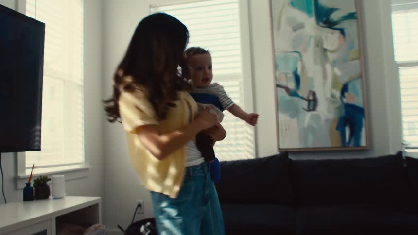 A mother dancing and smiling with her child in her arms in a living room