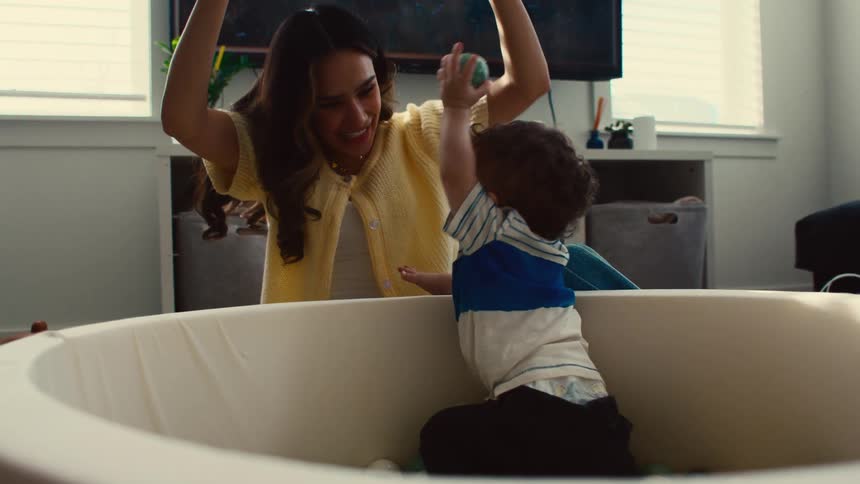 A mother and her son play with balls in a ball pit