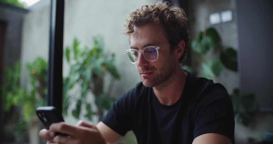 A man holds and uses a phone with both hands in front of him