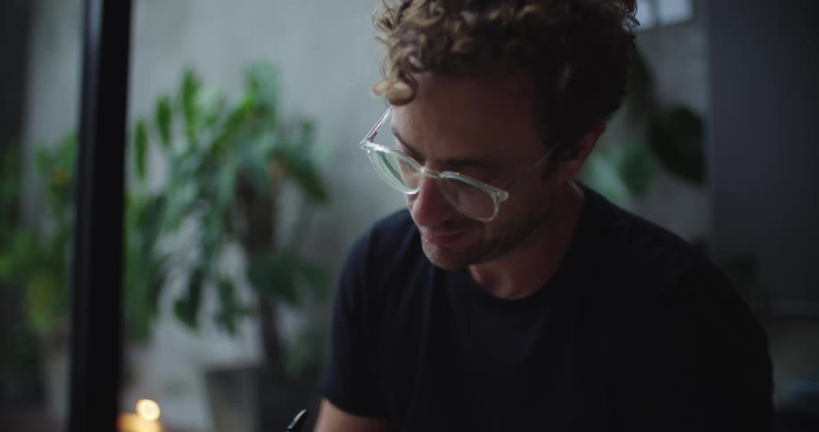Man sitting indoors and writing in a book