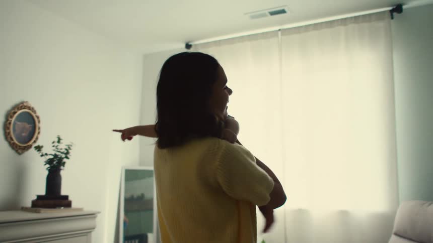 Woman picks up baby from bed and holds him over her chest