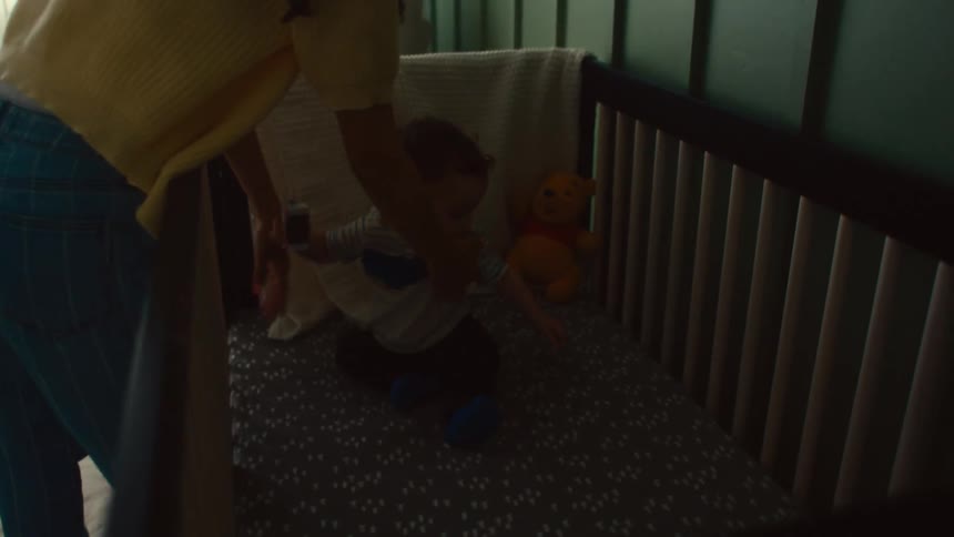 A mother is putting her son in the crib
