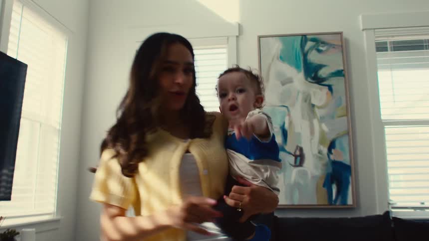A mother is dancing in the living room while holding her son in her arms