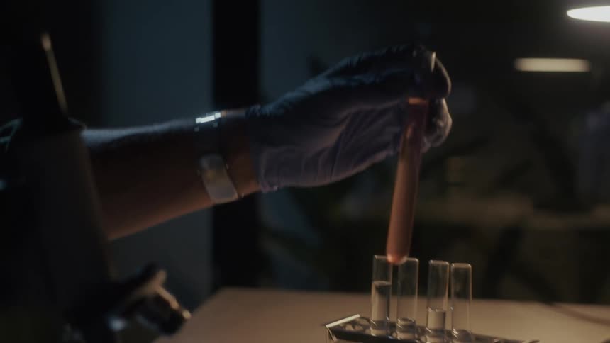 Lab technician picking up a test tube filled with liquid