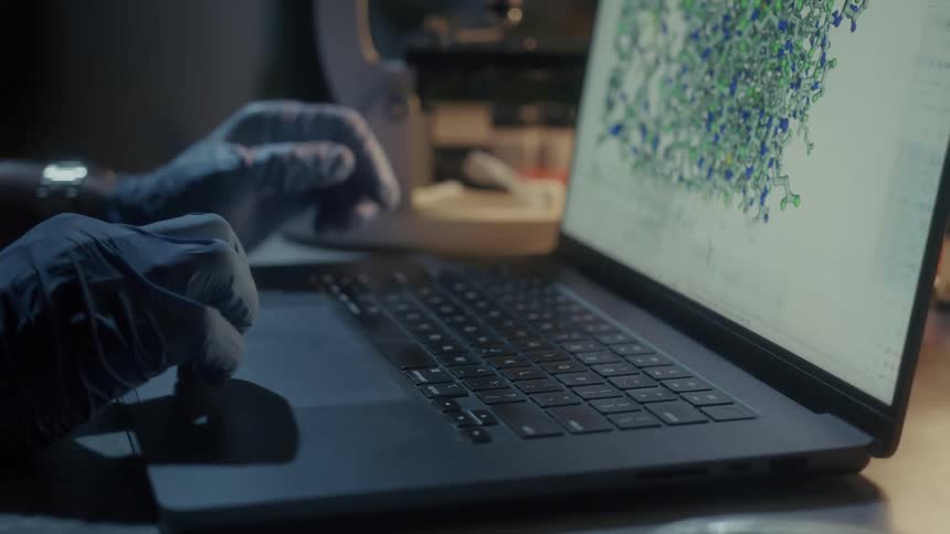 A man typing and analyzing chemical particles on his laptop