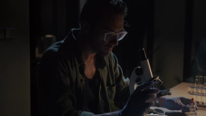 A scientist is examining something in a petri dish