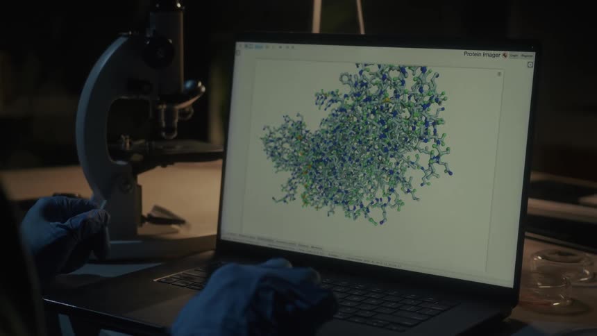 A scientist intently studies a 3d model of a protein structure on a laptop screen likely engaged in research or analysis