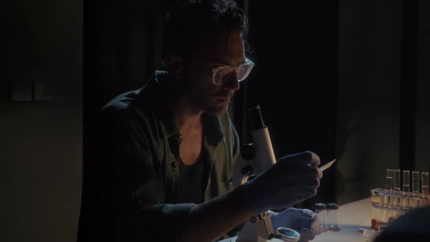 A man picks up a glass slide in places it on a microscope