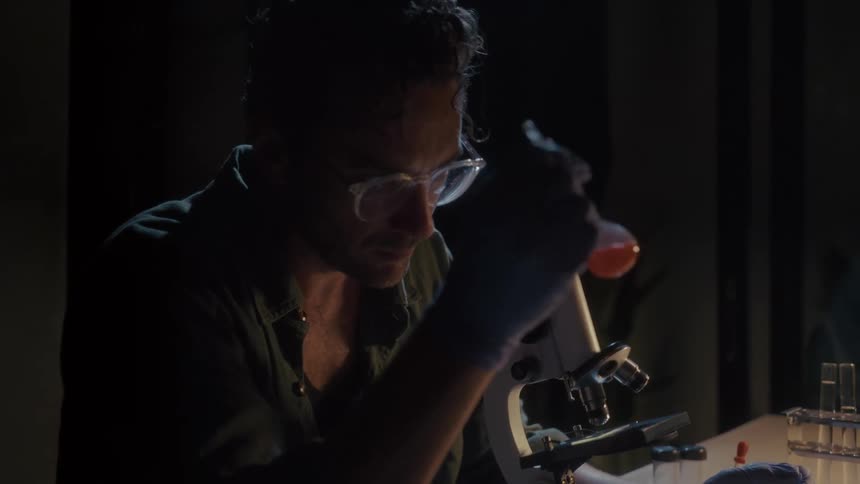 A man shakes and carefully inspects the contents of a beaker