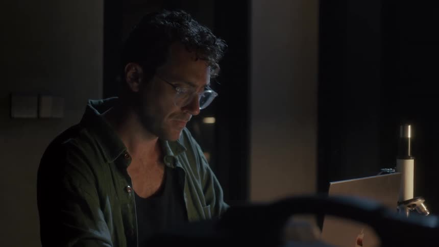 A man sits at his desk and looks at his computer