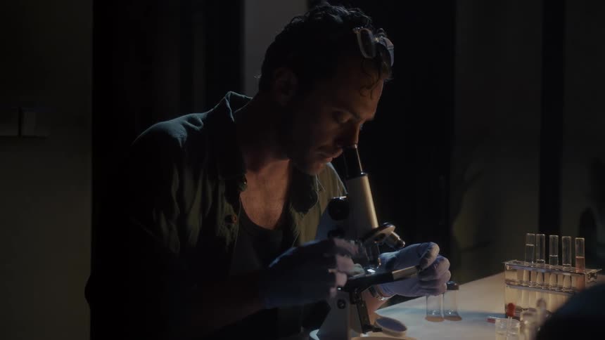 Man places and inspects a glass slide with a microscope