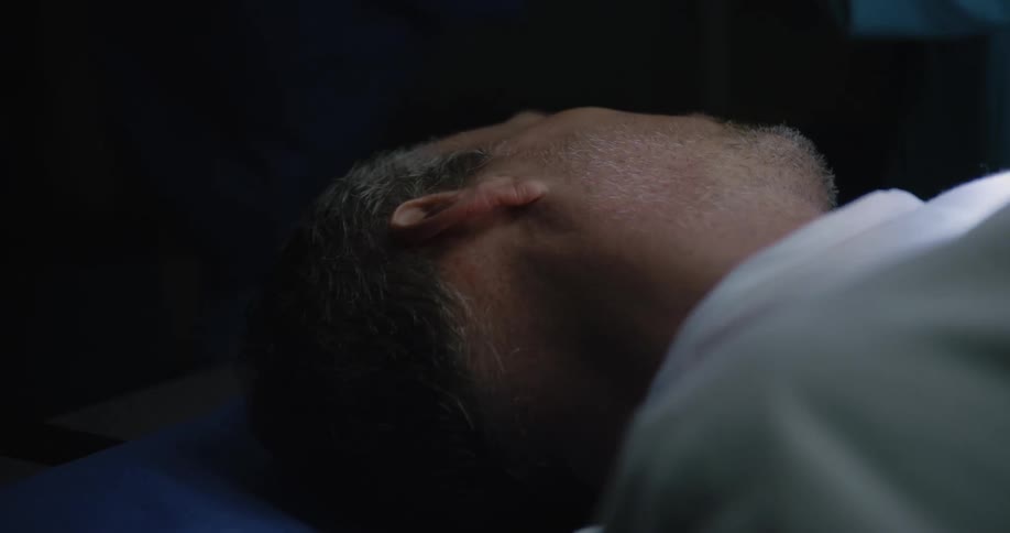 Pair of hands pressing down on the heart of a patient on a stretcher in a hospital operating room