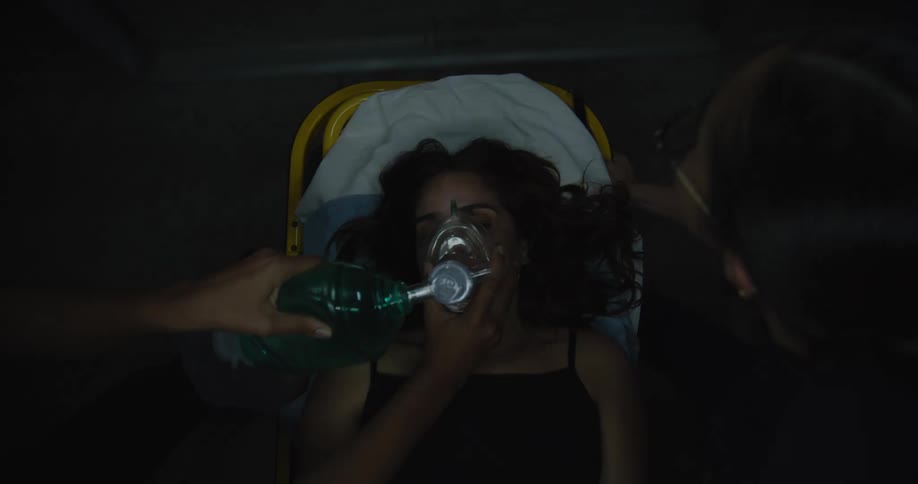 Two nurses accompanying a woman with an oxygen mask on a stretcher