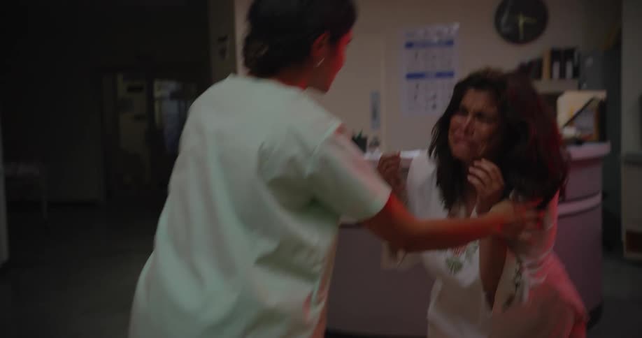 A desperate woman crying while her husband is being wheeled in by nurses in the emergency room