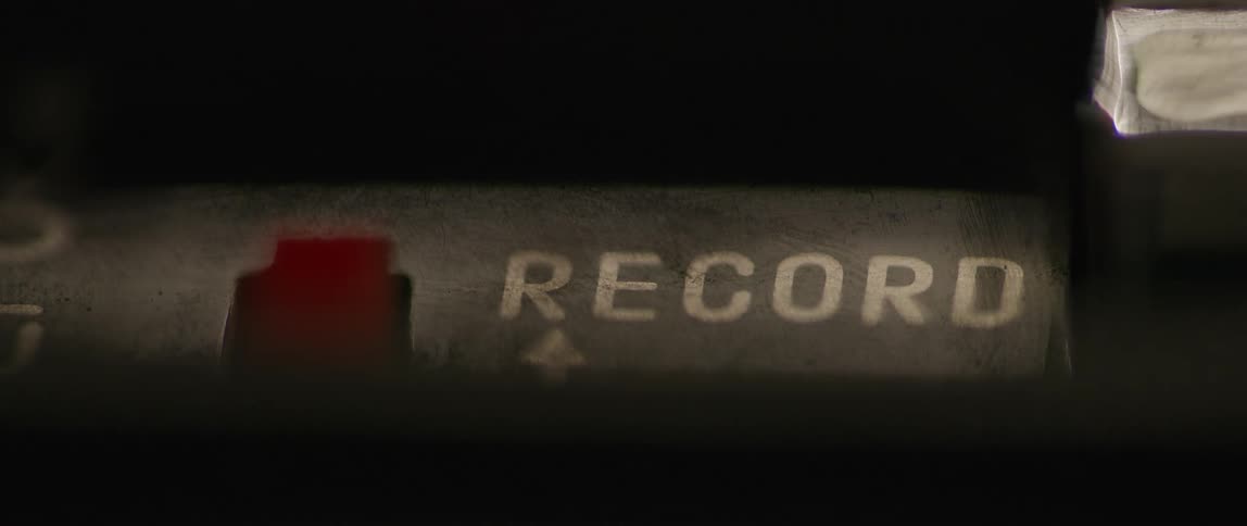 A person hits the record button on an old piece of equipment