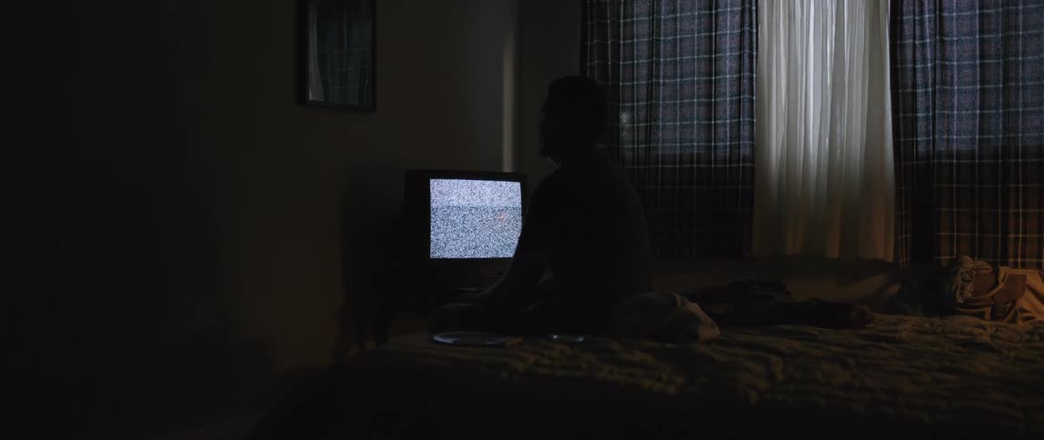 A man watches the static on the tv in his bedroom