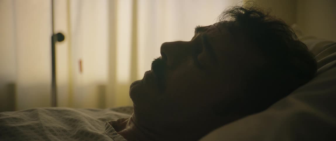 A hispanic man is laying in a hospital bed suffering