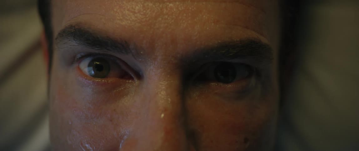 A sick man in bed opens his eyes in pain