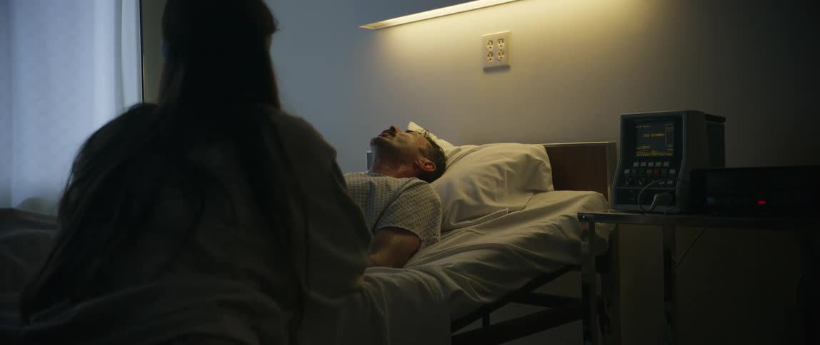 Woman tries to comfort a suffering patient while sitting next to him in the hospital