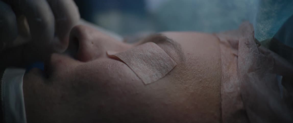 A patient is having their eyes taped shut in the operating room