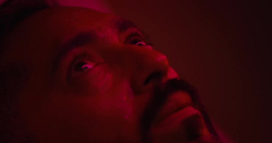 Red lights flash on the mans face in the dark room